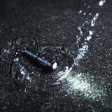 Nebo Columbo Key Chain shown in a puddle of water