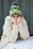 Pachamama Flock of Sheep Bobble Beanie on model wearing a white cardigan and hiding her face, which is kinda better...