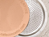 Close-up of a Cafe Concetto Moka Filter Disc 57.5mm and a Bialetti moka stove top espresso coffee maker disc
