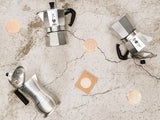 A Cafe Concetto Moka Filter Disc - Superfine 57.5mm shown being used with various compatible coffee makers