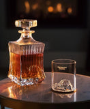 Gilded Peaks Helvellyn Glass tumbler shown from the front next to a carafe of whiskey