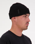 Mons Royale McFish 100% Merino Beanie in Black with cuff rolled up on a male model
