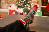 Solmate Crew Socks in the colour Yuletide, shown on a foot shape, with a christmas background