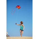 An image of a girl flying a HQ Sleddy Rainbow foldable kite on a beach