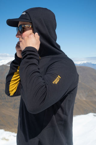Mons Royale Approach Merino Shift Fleece Hood in the colour Black shown with the hood up on the ski slopes