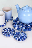 Pachamama Blue Finisterre pebble coaster next to mugs and a teapot atop a trivet