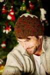Pachamama Christmas Pudding Hat on hunky man by a Christmas tree