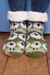 Pachamama Flock Of Sheep Slipper Socks with the cuffs turned down showing fleece lining on wooden flooring