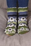 Pachamama Flock Of Sheep Slipper Socks standing on a sofa