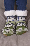Pachamama Flock Of Sheep Slipper Socks with the cuffs turned down showing fleece lining standing on a sofa