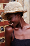 Pachamama Hemp/Cotton Sun Hat with wire brim shown in the colour Natural, with the model laughing and looking to the side