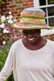 Pachamama Striped Hemp/Cotton Sun Hat with wire brim shown in multi colour stipes showing the model smiling and looking down