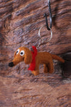 Pachamama Steven The Sausage Dog Keyring hanging off a hook on a rough wooden background