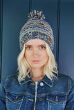 Pachamama Langtang Bobble Beanie in Blue. A blue and white striped bobble beanie worn by a female model