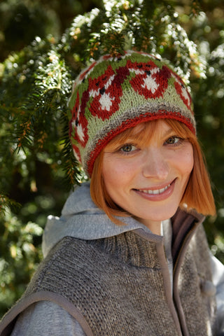 Pachamama Skulk Of Foxes Beanie shown worn by a model under an unidentified conifer tree